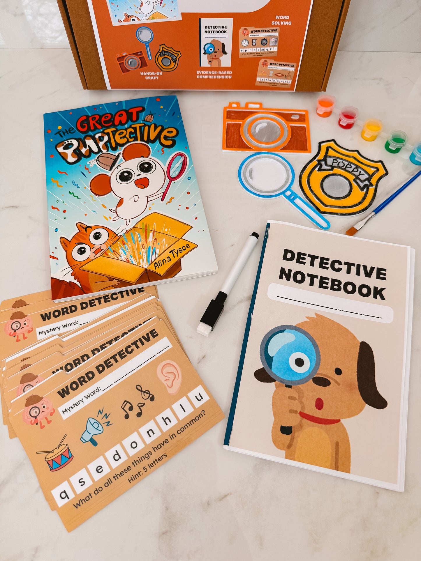 Children's detective-themed activity set with book, notebook, and cards on a light surface.