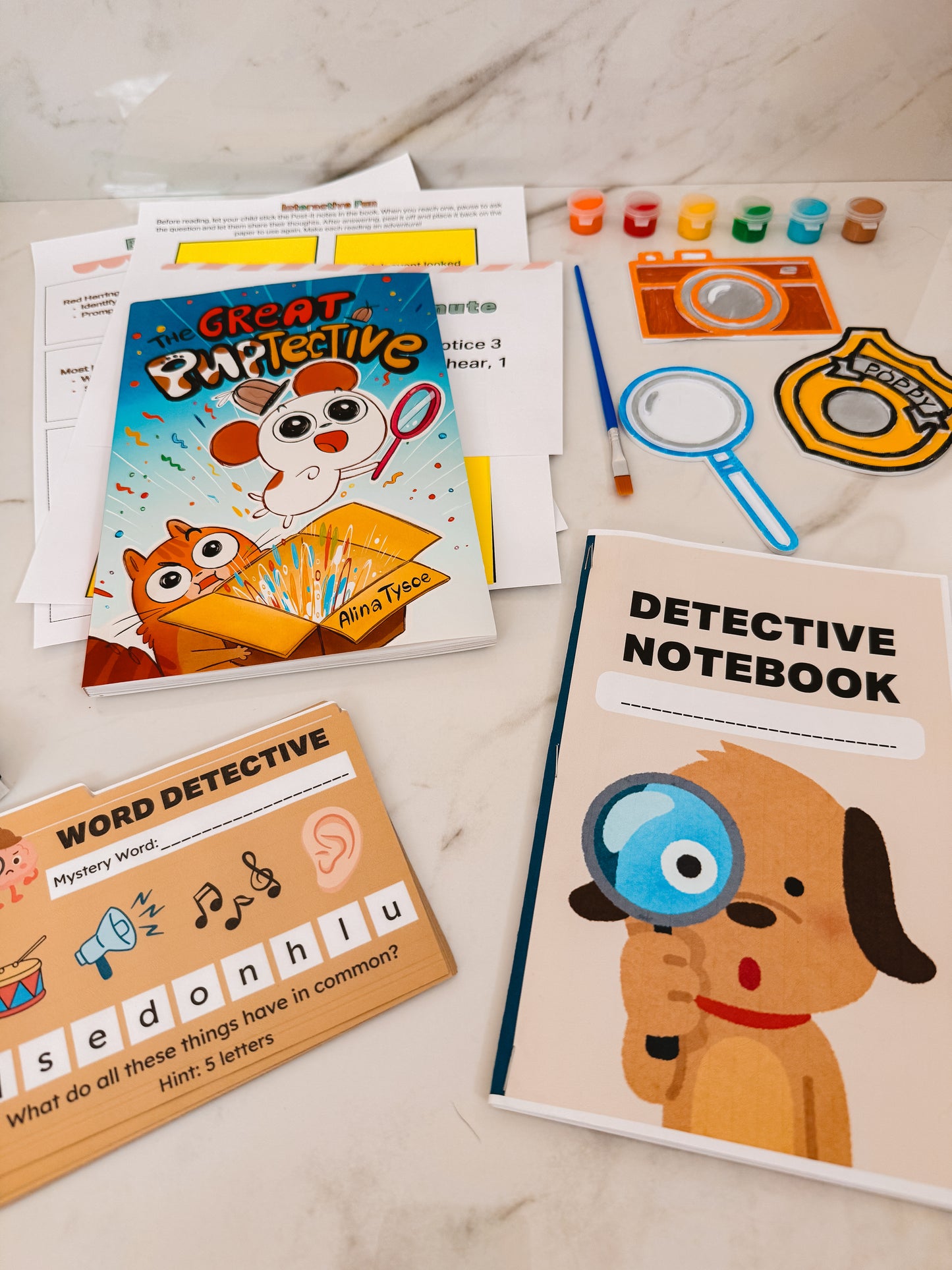 Children's detective-themed books and materials on a marble surface
