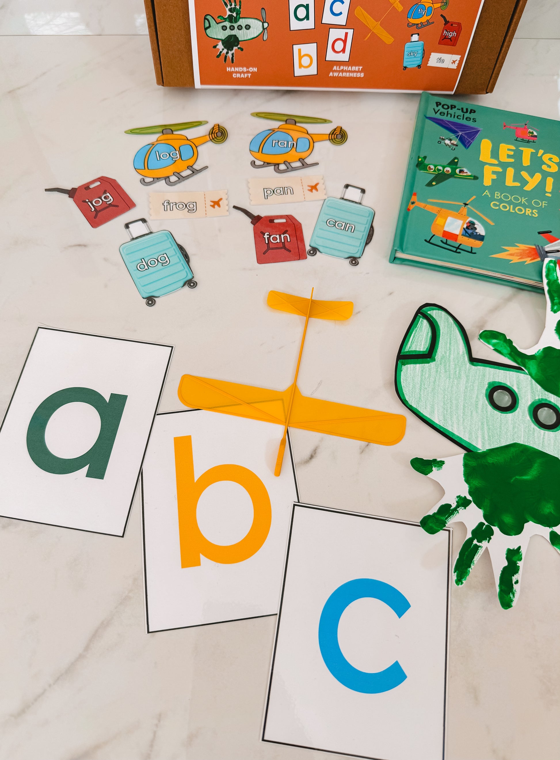 Educational children's items including alphabet cards, a toy helicopter, and a book on a light surface.