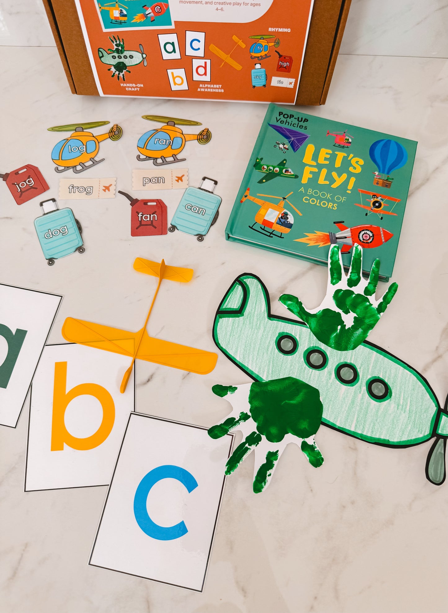 Educational children's materials including a book, cards, and handprint craft on a light surface.