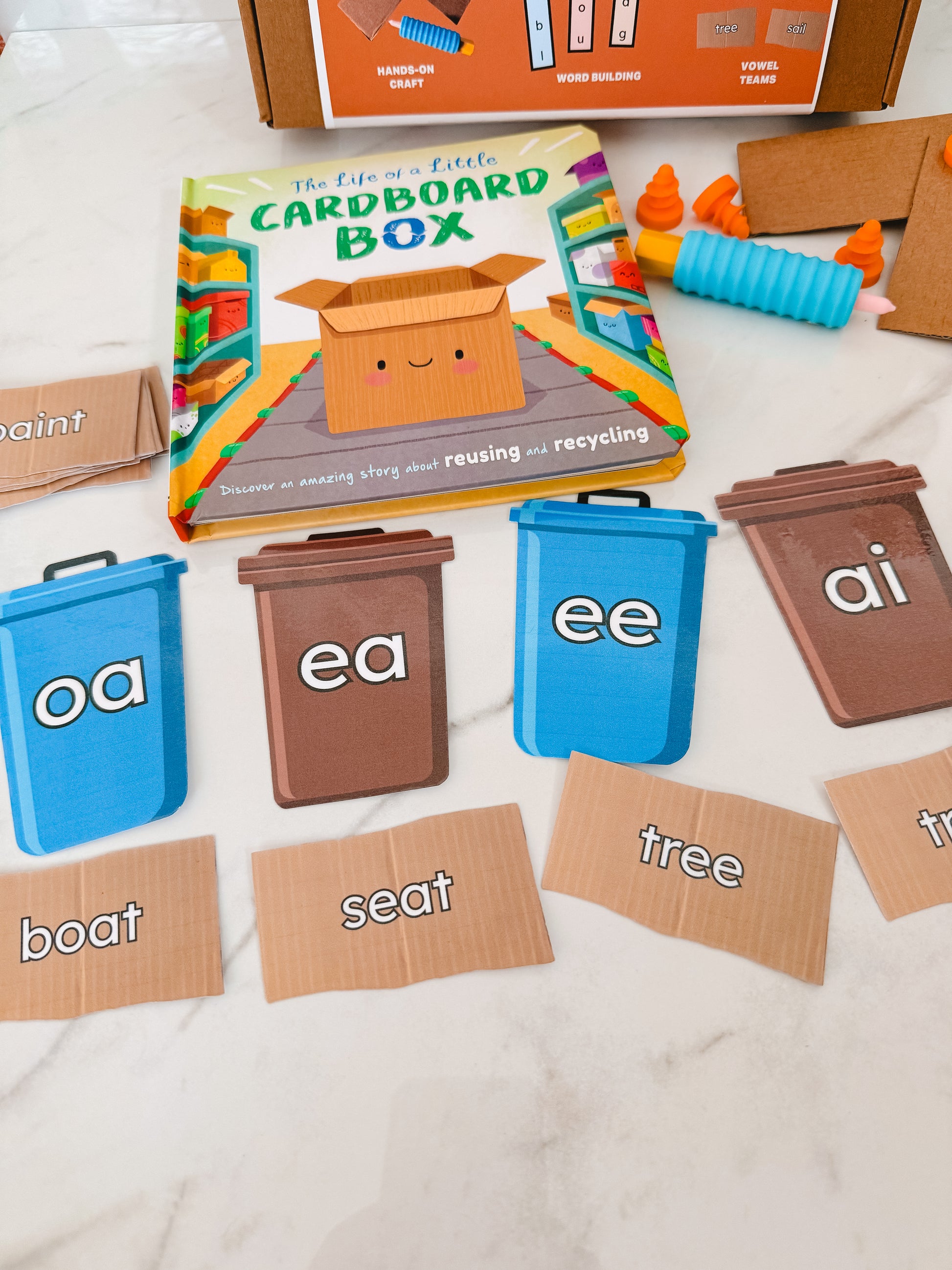 Educational materials for teaching phonics with colorful bins and word cards on a white surface.