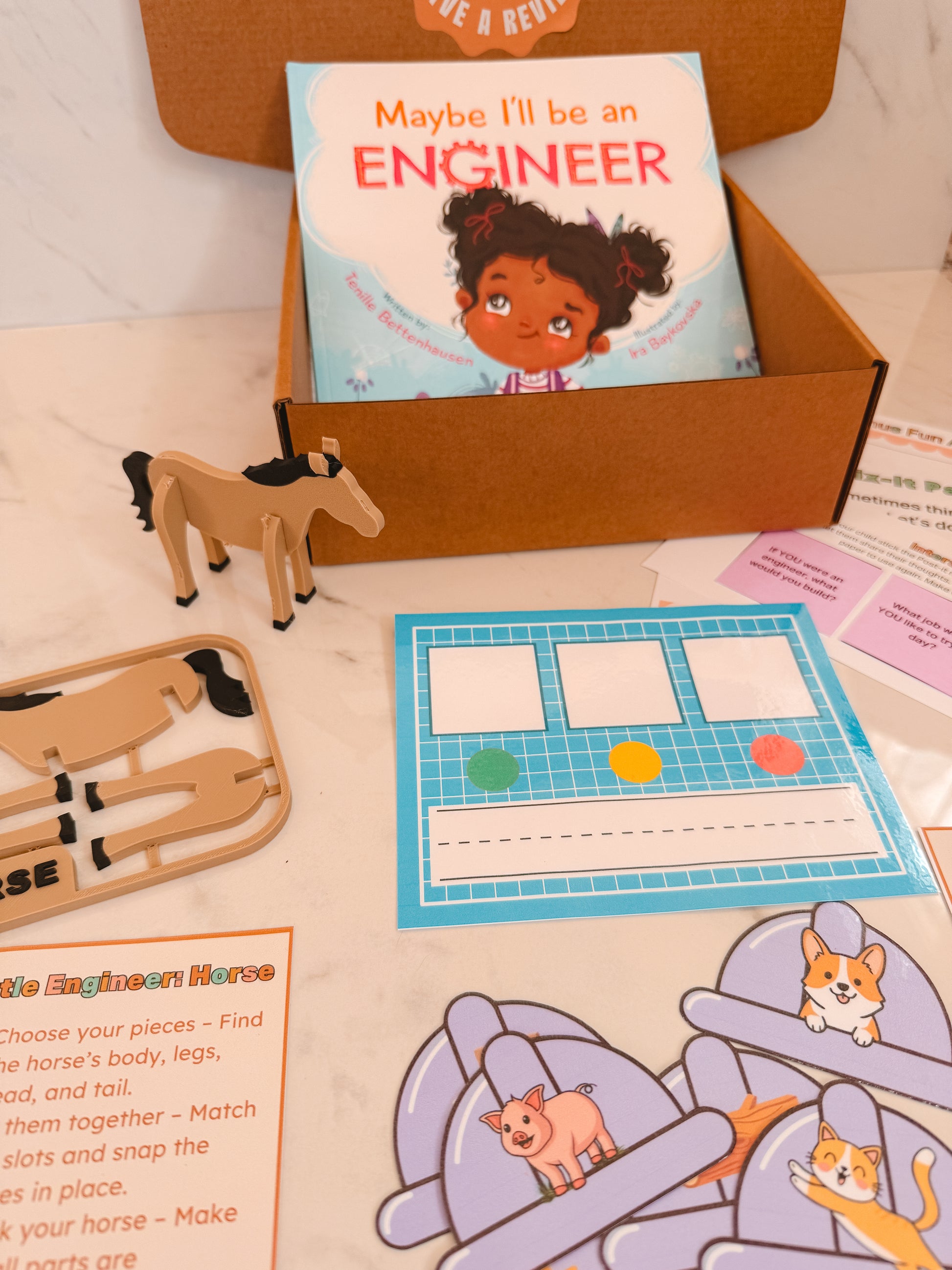 Educational materials including a book titled 'Maybe I'll be an Engineer' and toy pieces on a table.