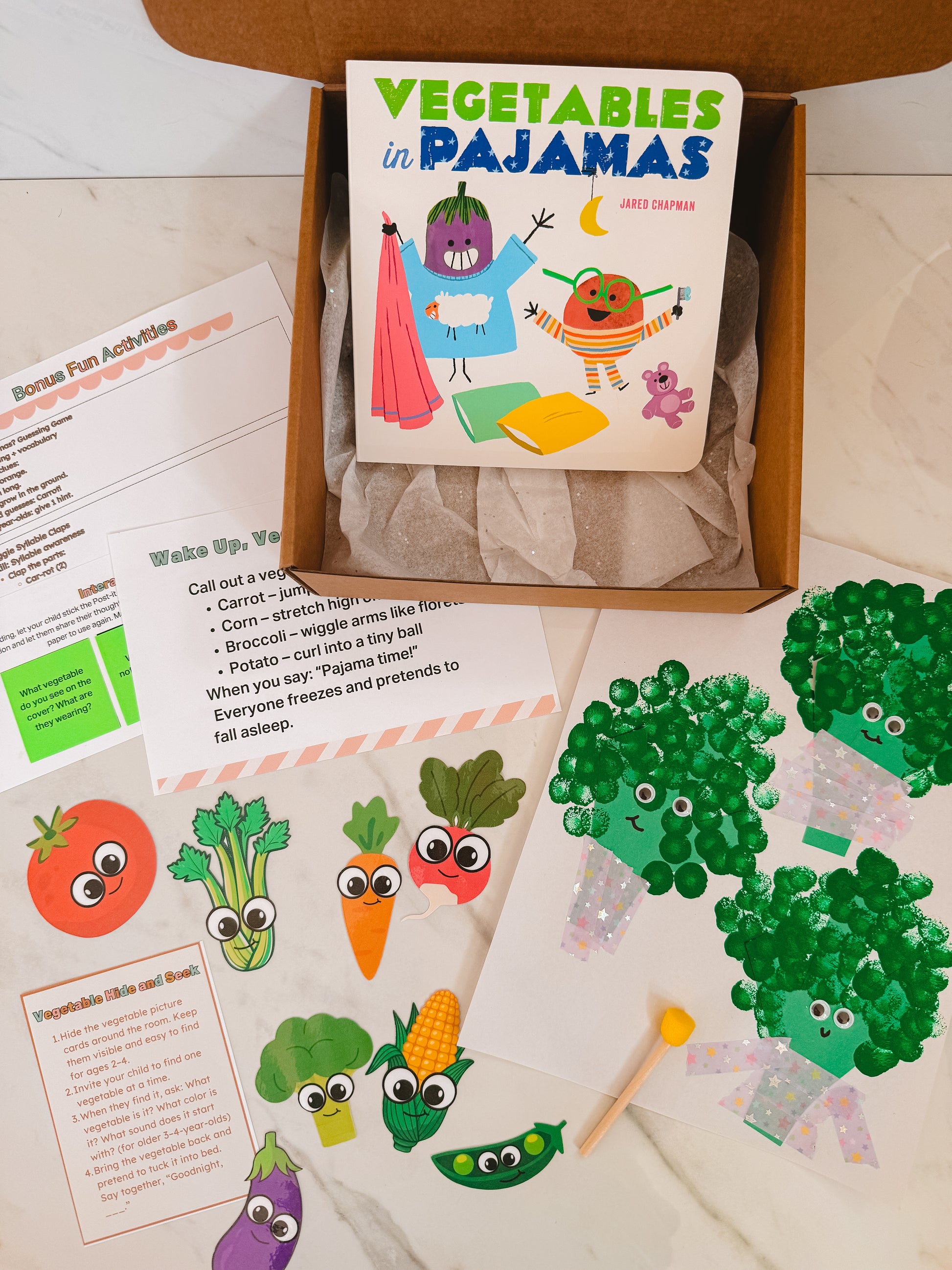 Children's book titled 'Vegetables in Pajamas' with related activities and illustrations on a wooden surface.
