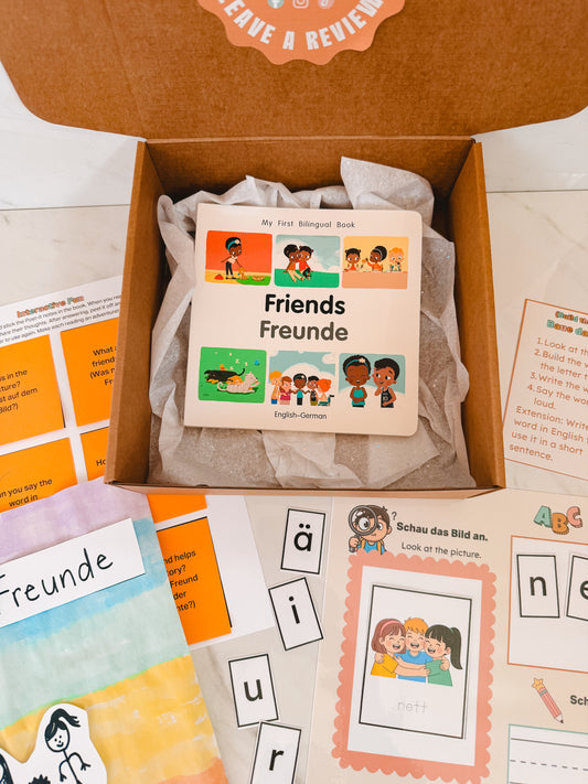 Educational materials including a book titled 'Friends Freunde' in English and German, flashcards, and activity sheets on a white background.