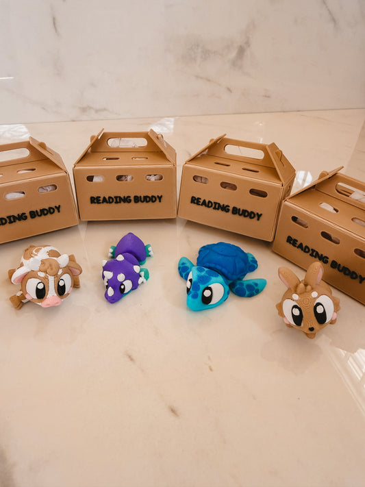 Four colorful animal plush toys in front of 'Reading Buddy' boxes on a light surface.