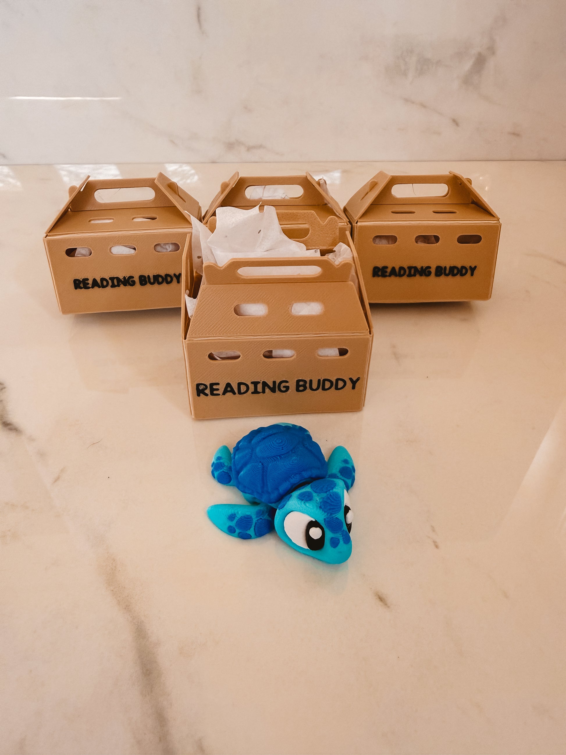 Blue turtle toy with 'Reading Buddy' crates on a marble surface